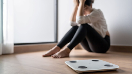 Sad woman upset bored of dieting Weight loss failÂ  Fat diet and scale sad asian woman on weight scale at home weight control - stock photo